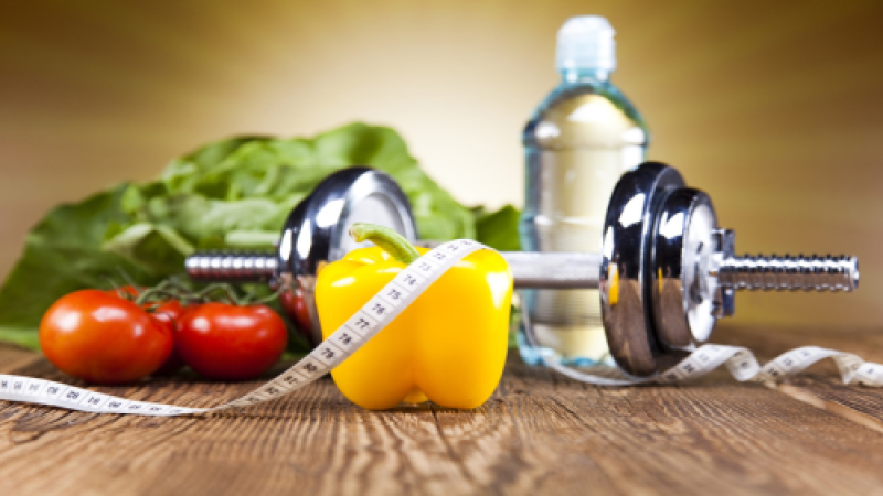 Fruit and a dumbell on a table, with a tape measure draped over everything