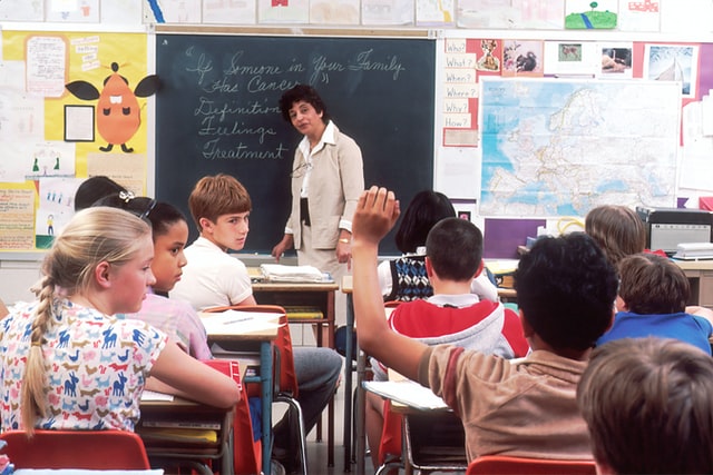 Kid raising his hand in a school classroom